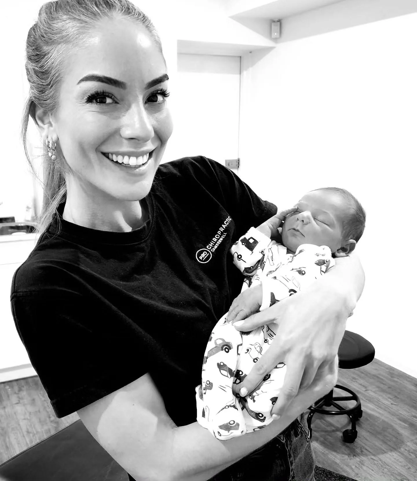 Pro Chiropractic practitioner in branded uniform cradling a newborn inside the clinic
